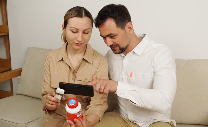 a couple using zoomax luna 6 handheld video magnifier to look at pill bottle